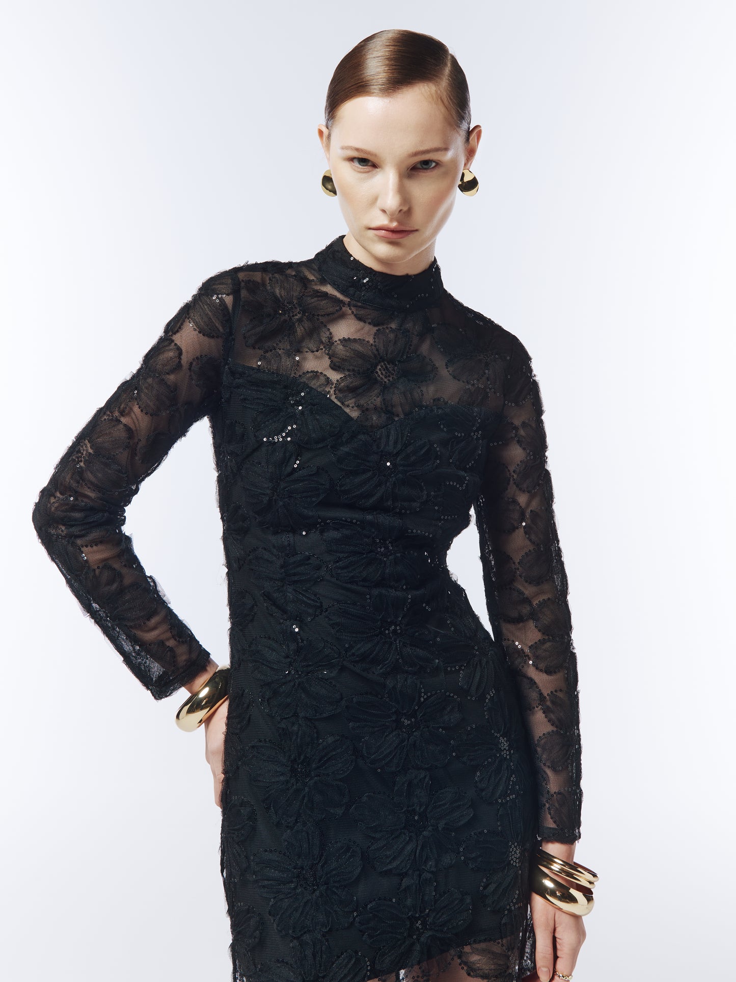 Close-up of floral embroidery and tonal sequins on black sheer mesh fabric.