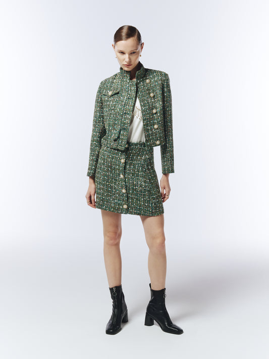 Model wearing SOUR FIGS Cropped High-Neck Tweed Jacket in Emerald Green Mélange with matching mini skirt, showcasing luxury pearl buttons and structured silhouette — perfect for AW25 smart casual and evening looks.