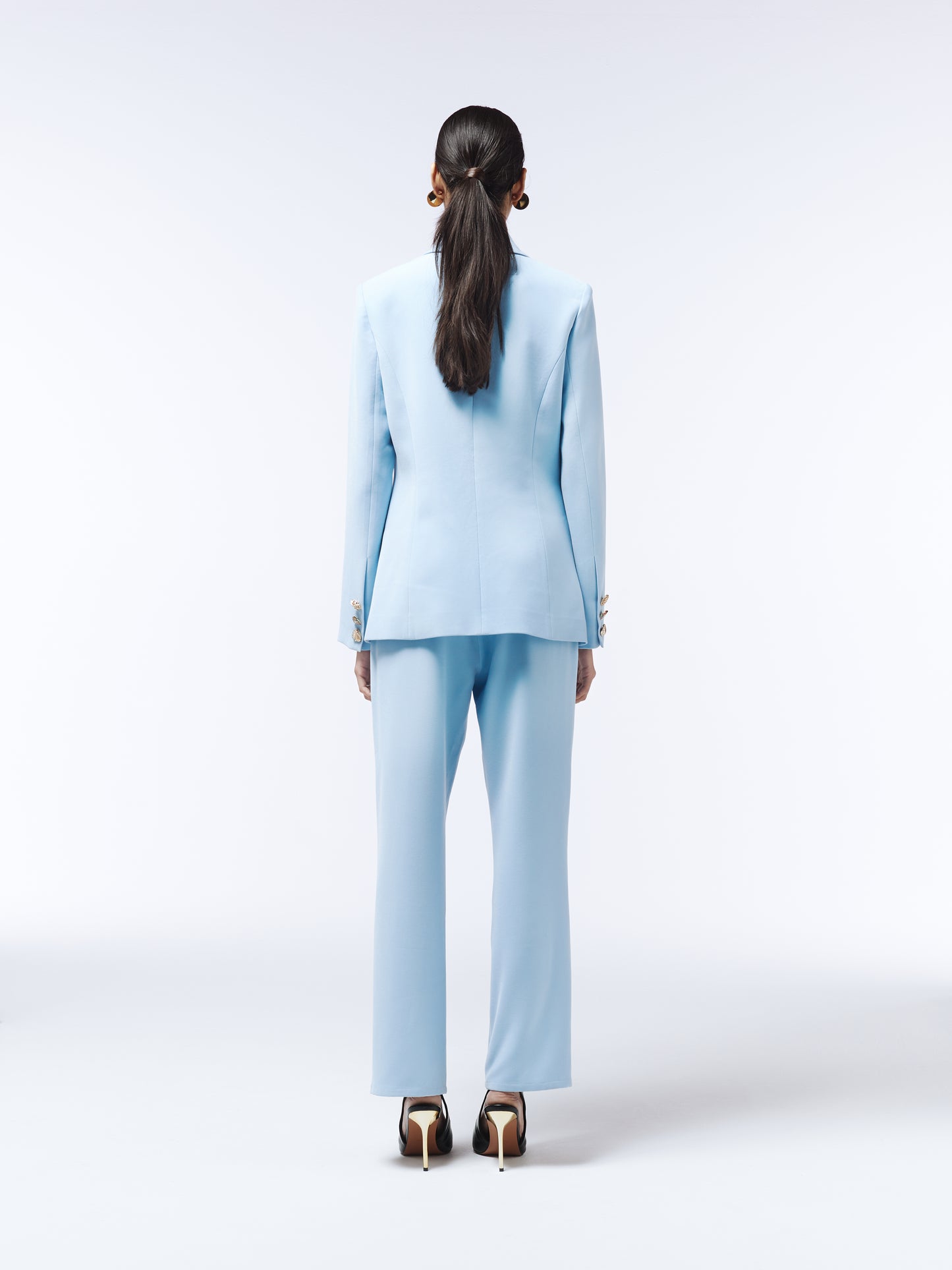 Model wearing sky blue high-rise trousers with floral T-shirt and black heels.