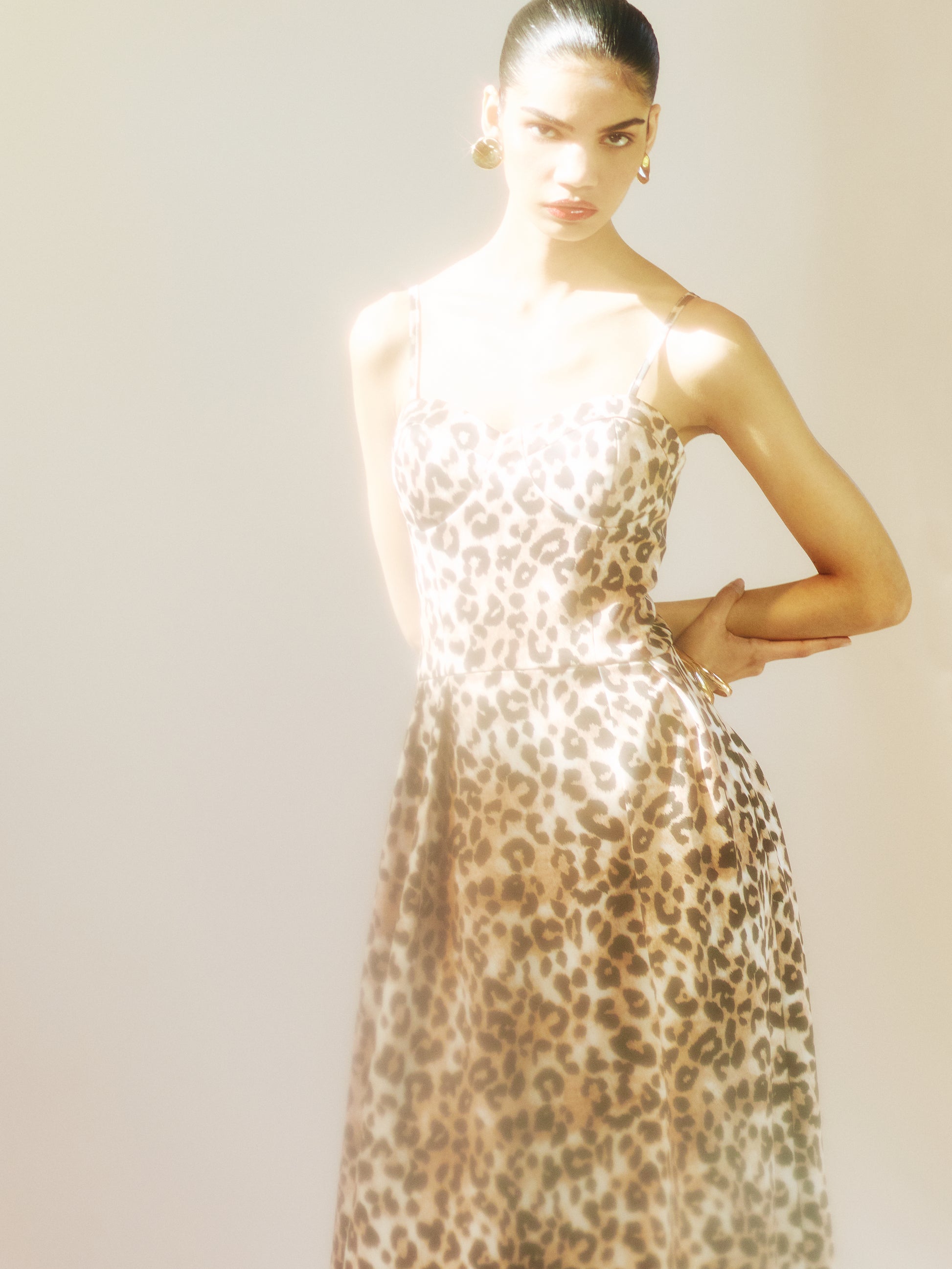 Leopard print midi dress styled for modern evening occasions with gold accessories.
