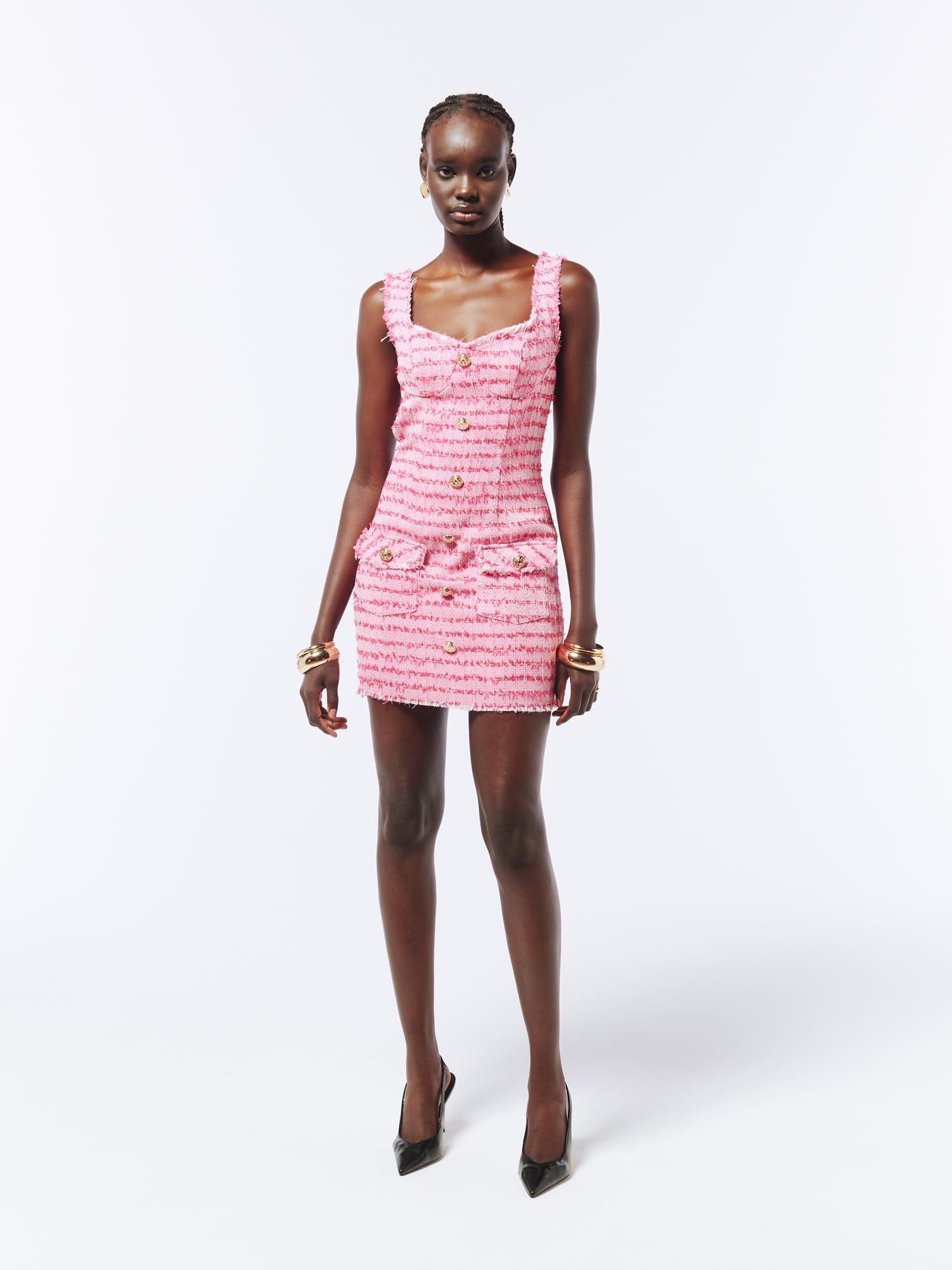 Textured pink tweed mini dress with frayed trim, a tailored slim fit, gold-tone buttons, and a refined yet playful aesthetic.