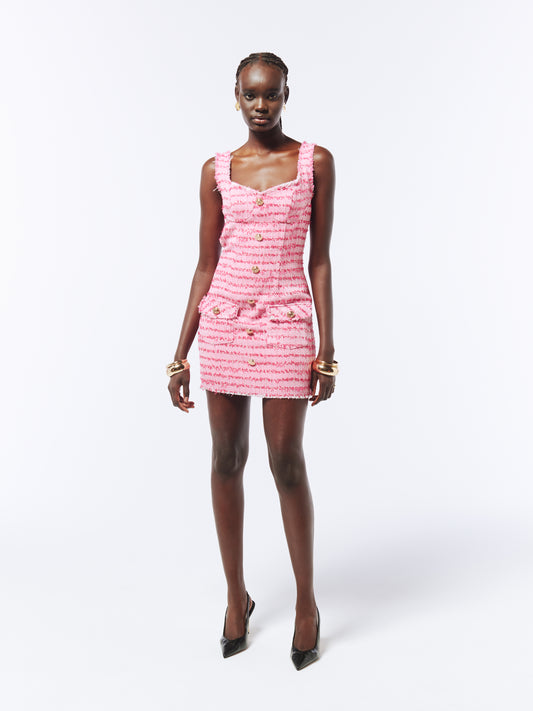 Textured pink tweed mini dress with frayed trim, a tailored slim fit, gold-tone buttons, and a refined yet playful aesthetic.