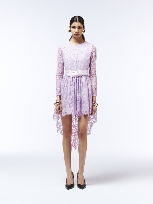 Back view of lilac lace occasion dress featuring sheer long sleeves and asymmetric hem.
