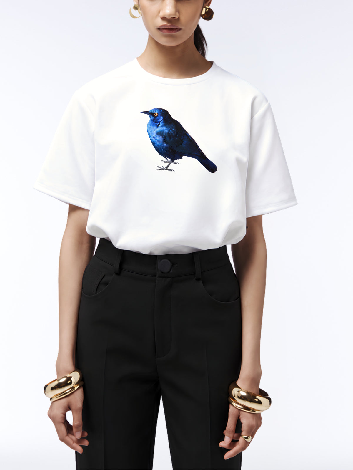 Close-up of the blue starling print on a white T-shirt tucked into black tailored trousers.