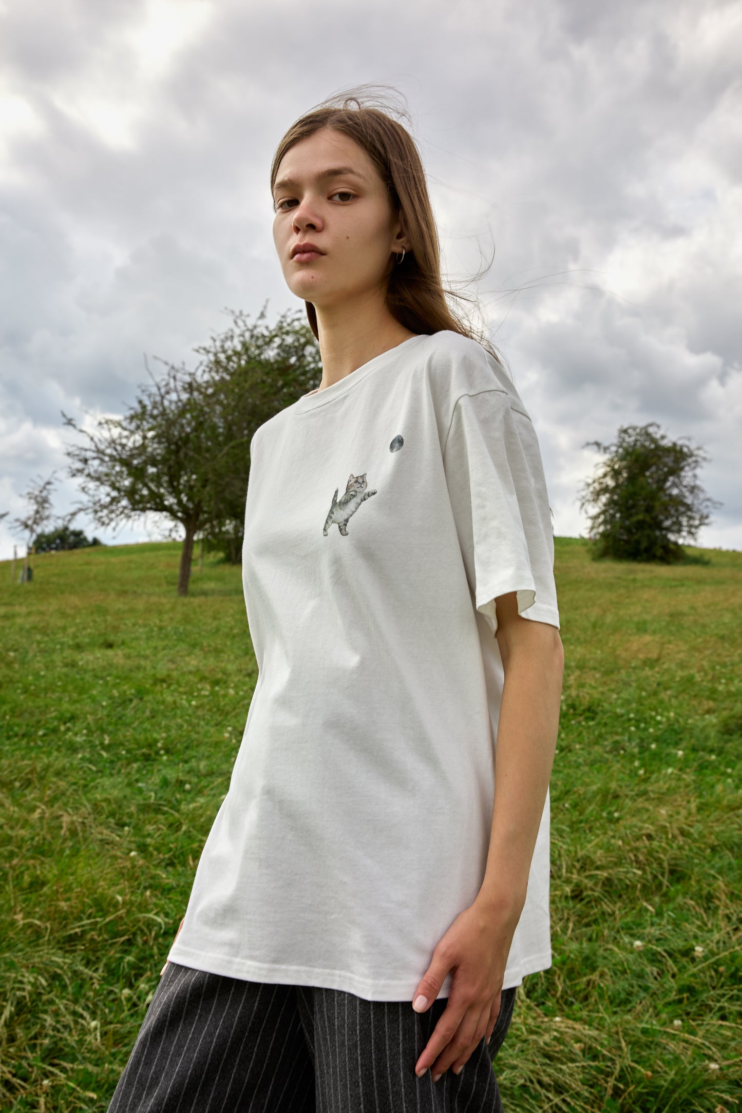 Women’s white short-sleeve T-shirt with cute cat chasing moon detail – SOUR FIGS design.