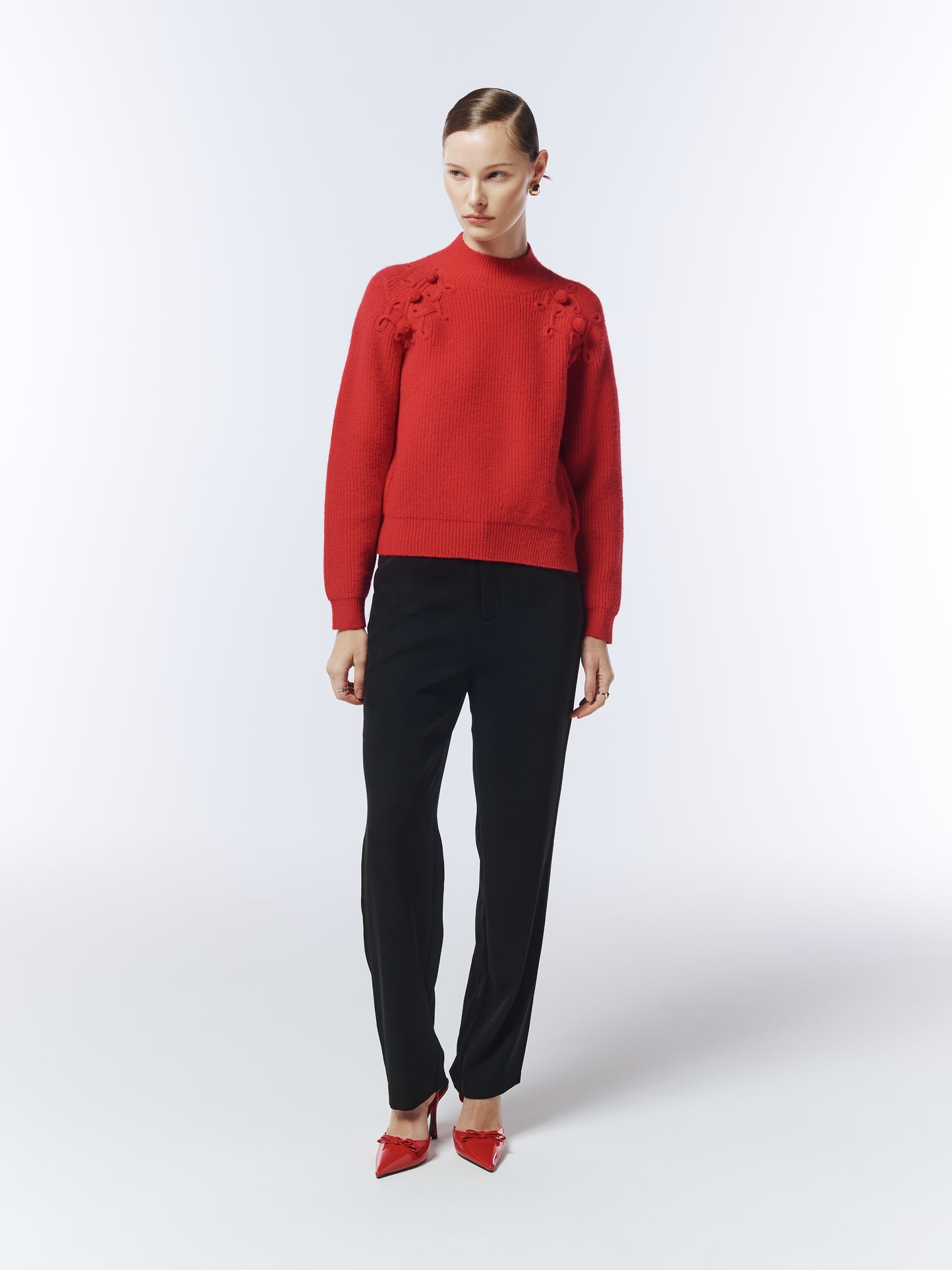 Model wearing SOUR FIGS Shoulder-Detail Bobble-Knit Jumper in Crimson Red with black trousers.