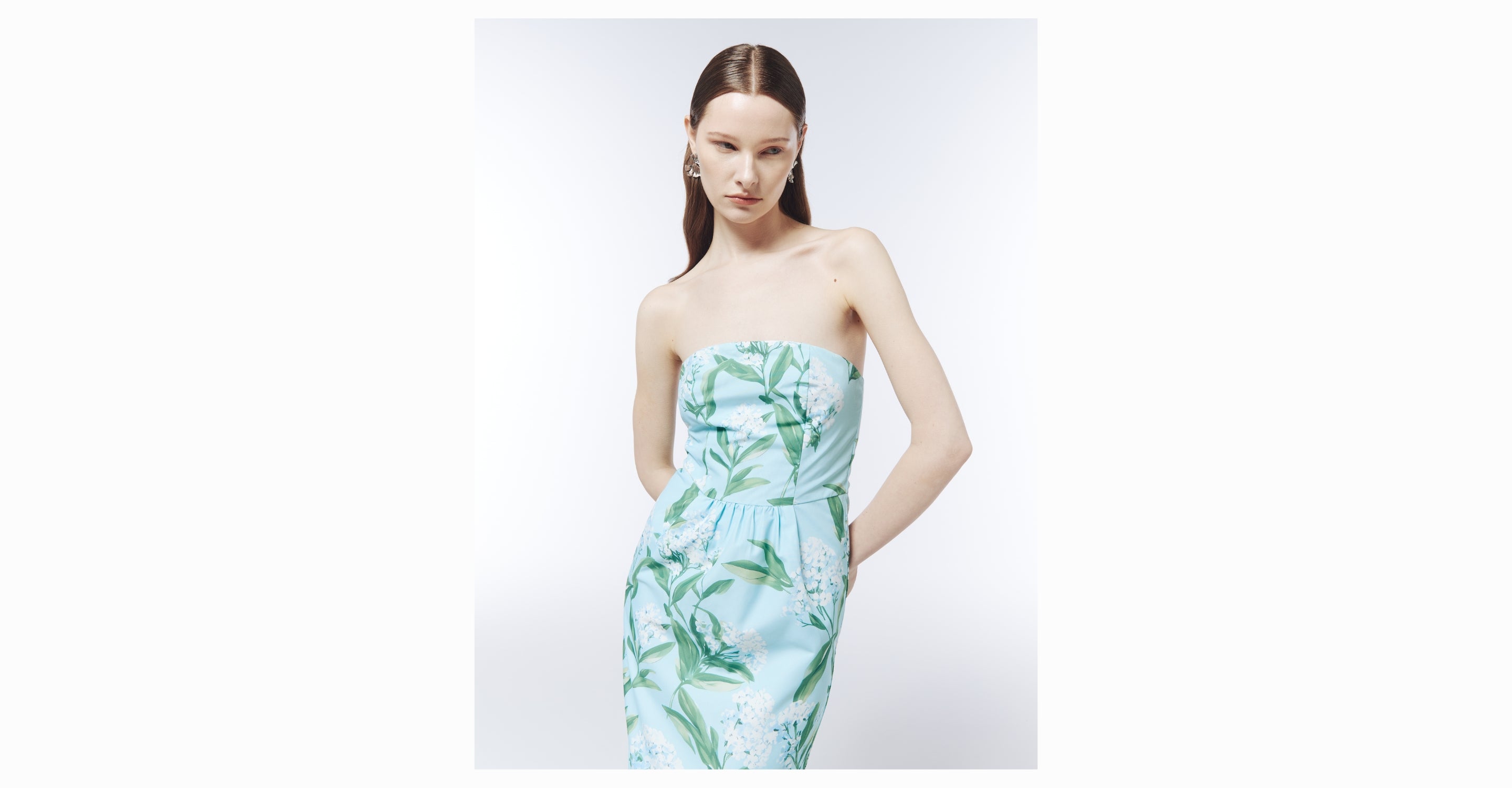 Woman wearing a strapless dress with green leaf pattern on a white background
