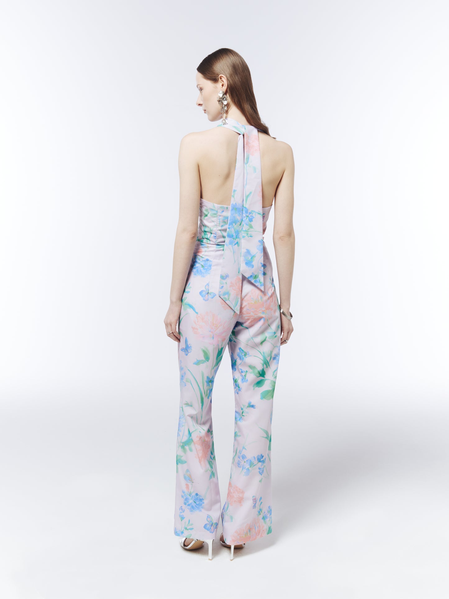 SOUR FIGS pastel floral jumpsuit featuring a plunging halterneck, twist-front waist and butterfly print.