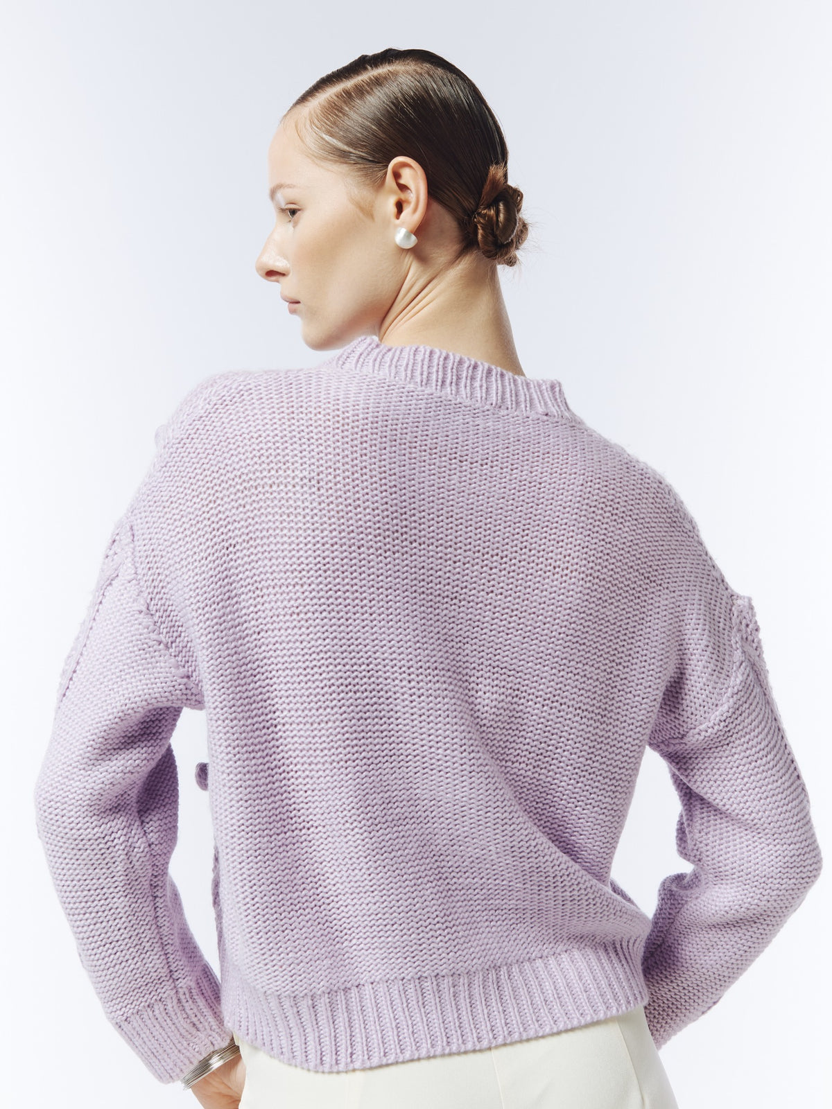 Soft lilac cable and bobble-knit jumper, back view on model showing plain knit back and ribbed hem.