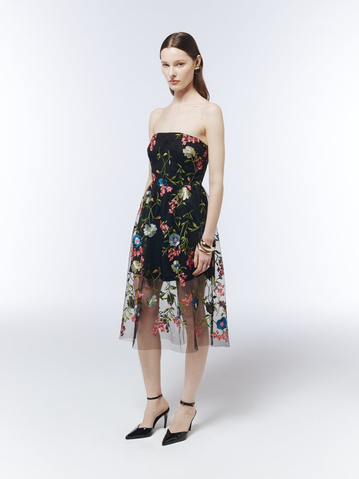 Black floral-embroidered strapless midi dress, three-quarter model view showing the defined waist and gently gathered mesh skirt.