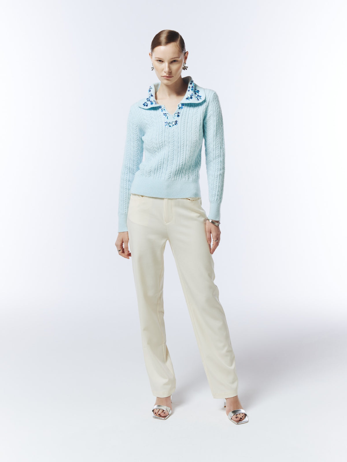 Ice blue hand-embellished cable-knit polo jumper, front model view showing long sleeves and ribbed cuffs and hem.