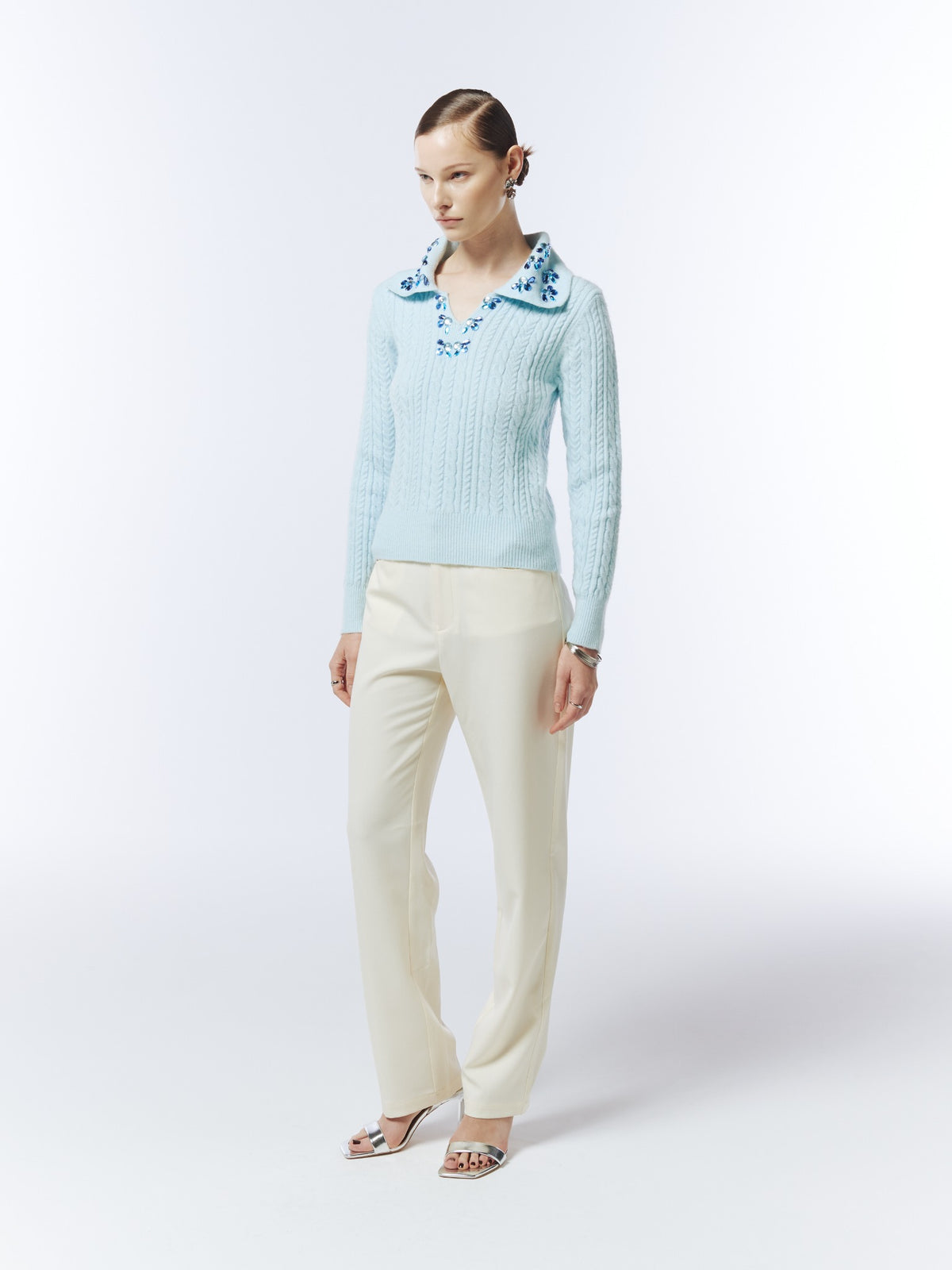Ice blue hand-embellished cable-knit polo jumper, three-quarter model view showing the jewel collar and relaxed fit.