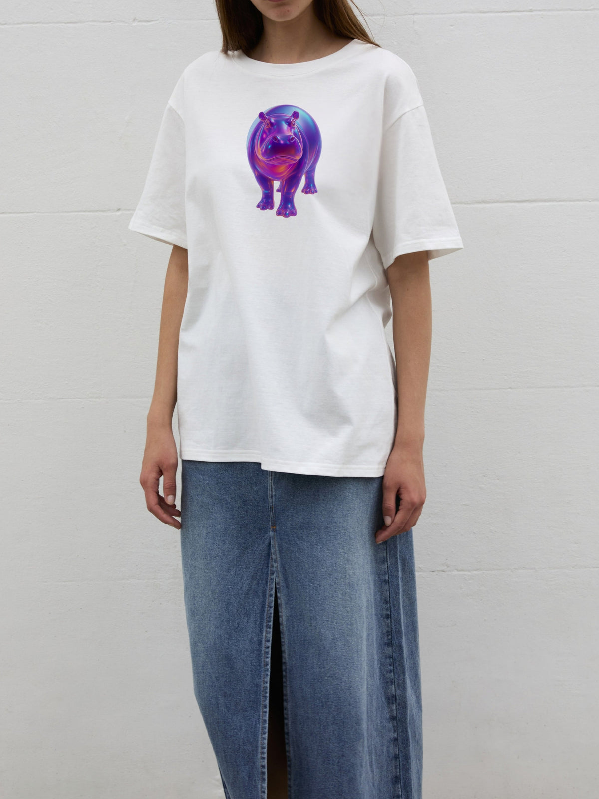 Front view of the SOUR FIGS Iridescent Hippo Print Unisex T-Shirt in White, worn loose with a blue denim skirt to show its oversized fit.