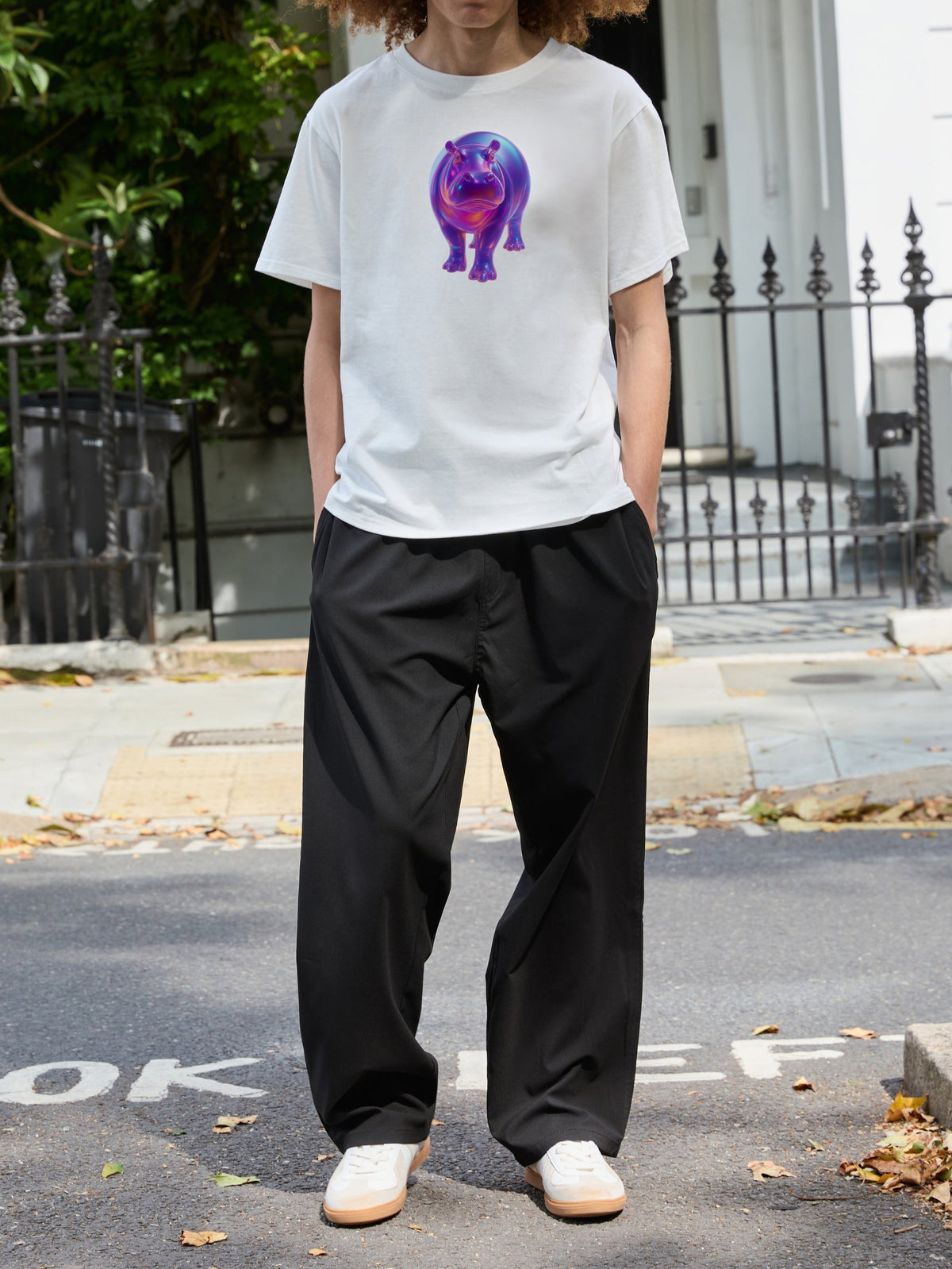 Full-length front view of a model wearing the SOUR FIGS white unisex hippo print T-shirt with black trousers and white trainers.
